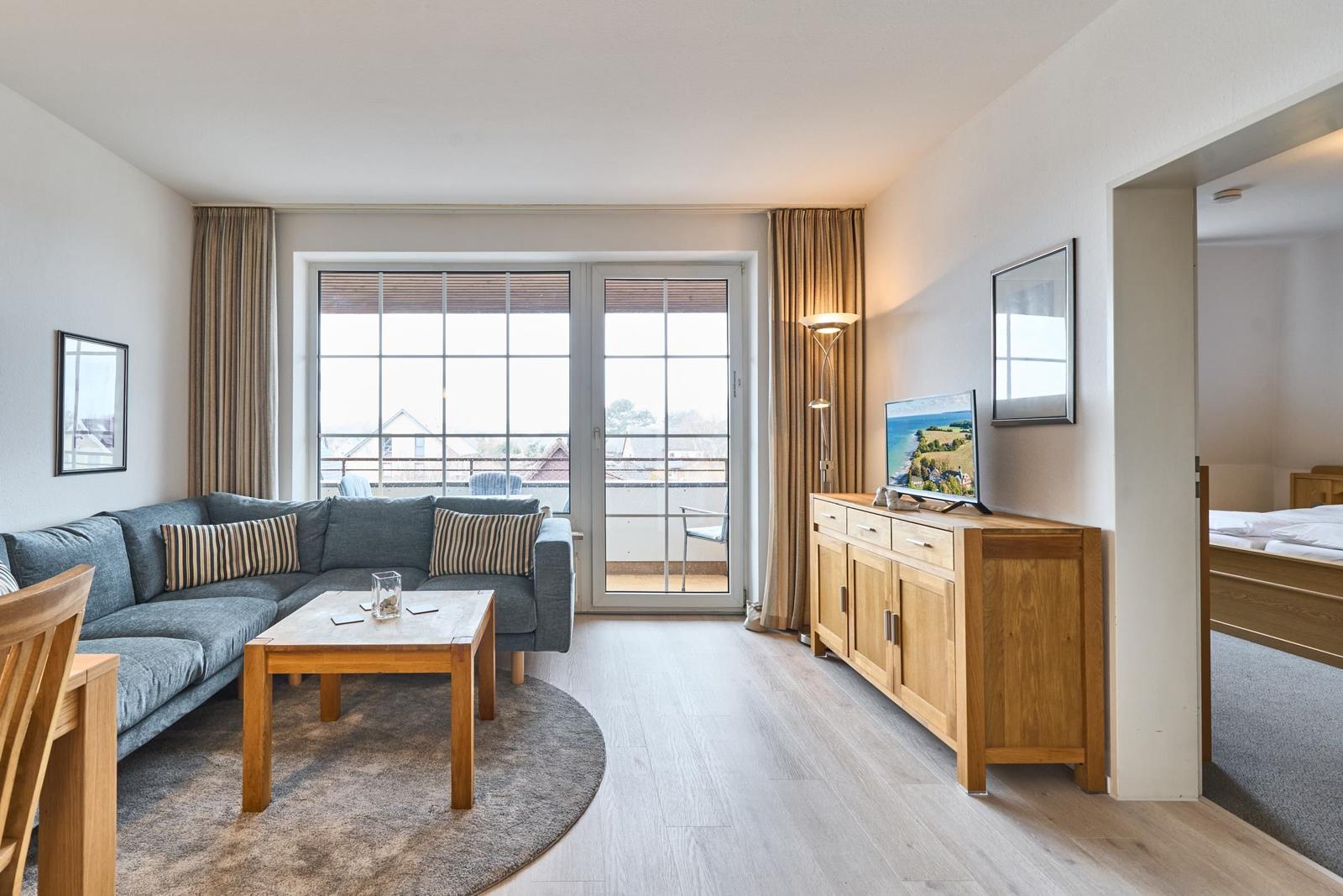 Wohnzimmer mit Sofa, Couchtisch und TV. Balkon mit Blick auf die Umgebung.