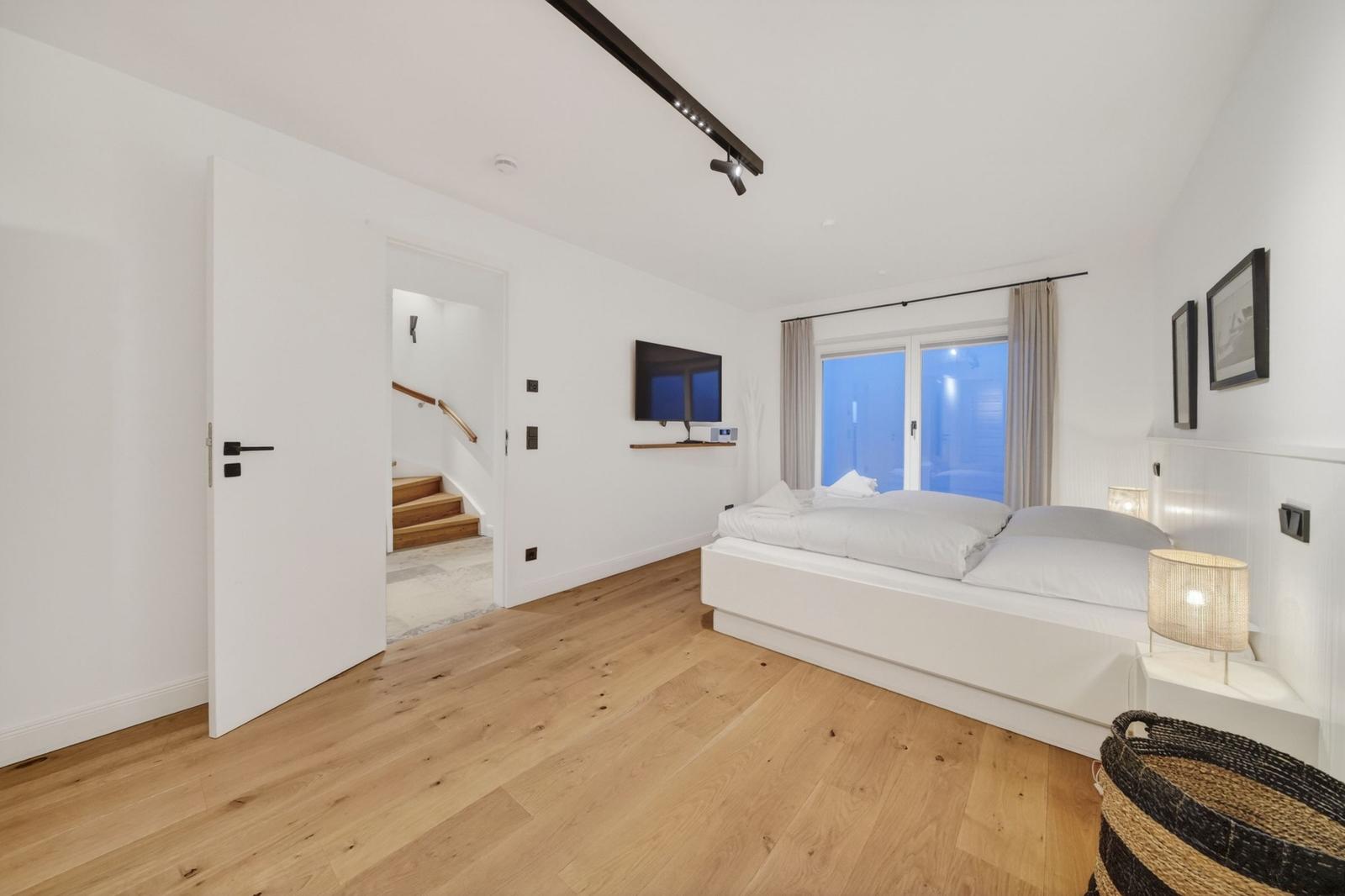 Schlafzimmer mit Bett, Fernseher und Blick auf Balkon