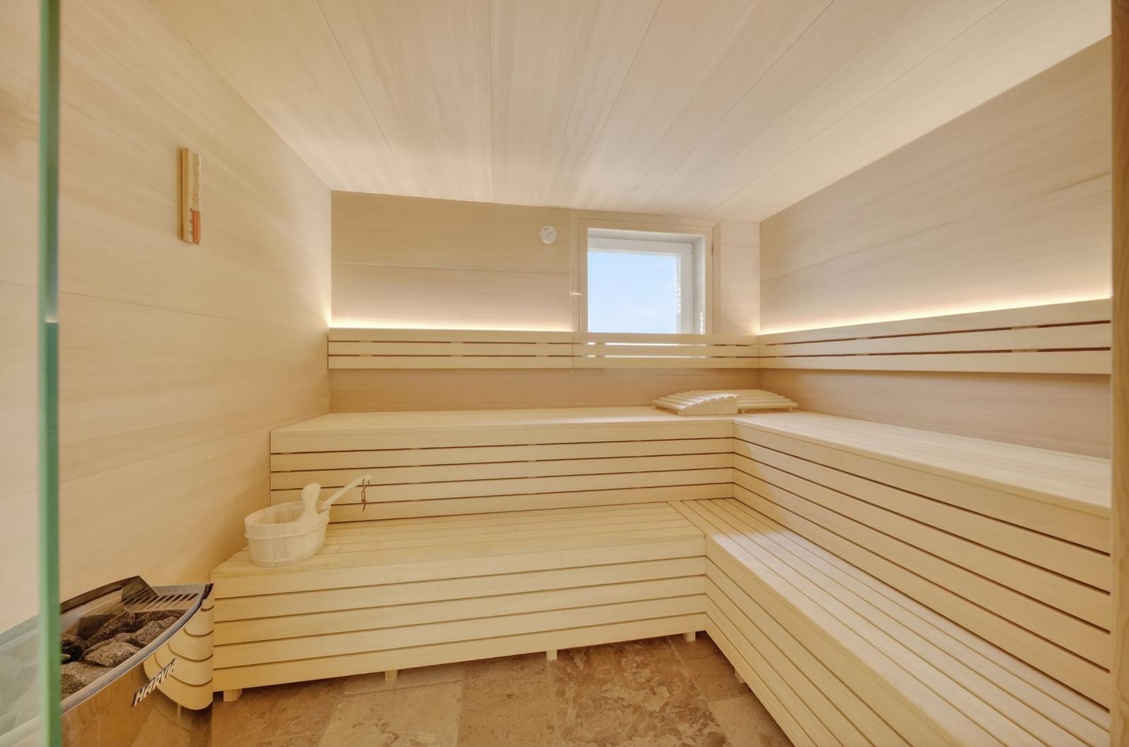 Sauna mit Holzbänken, Fenster und Steinkamin.