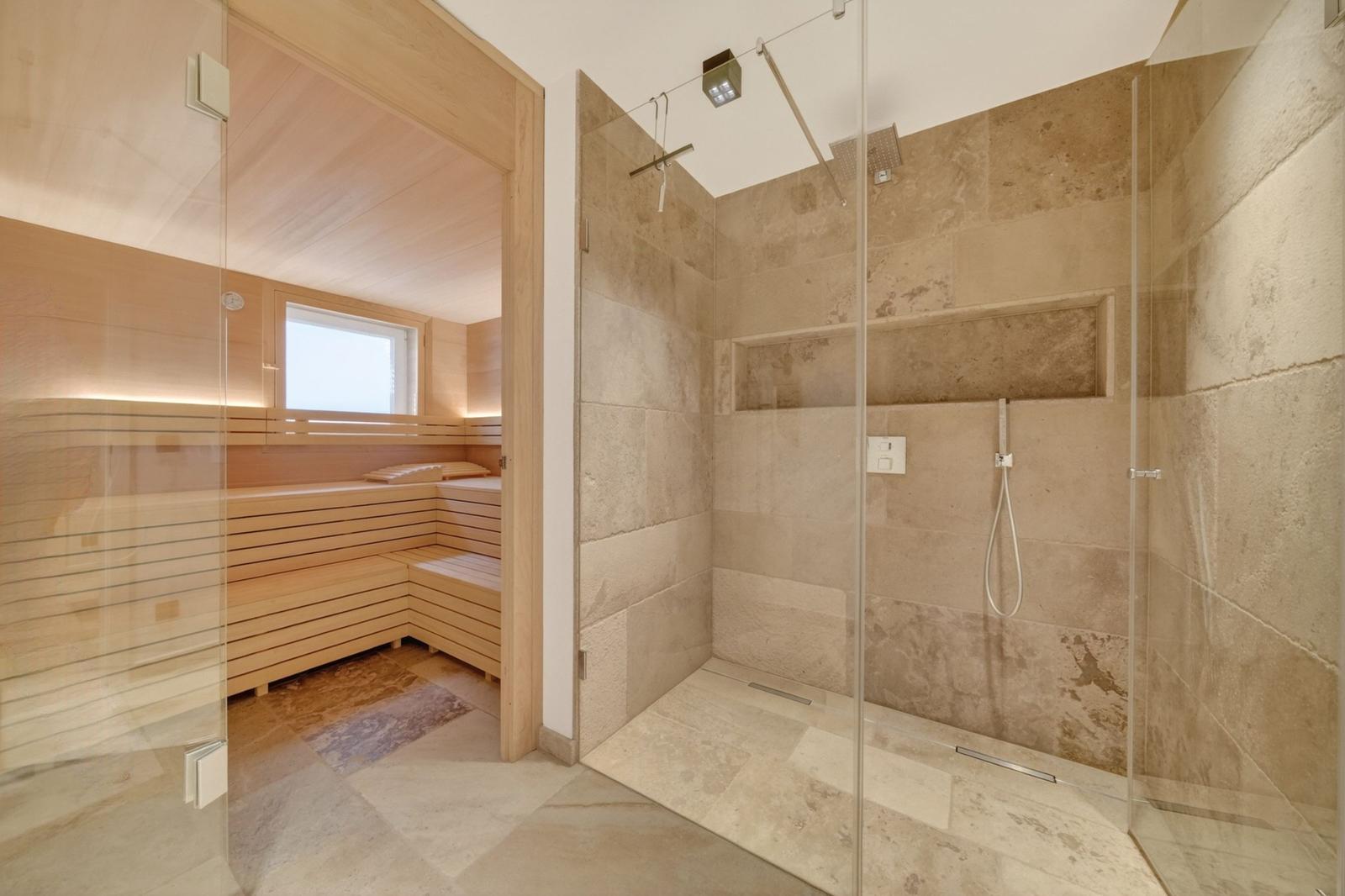 Dusche mit Steinwand und Sauna mit Holzbänken.
