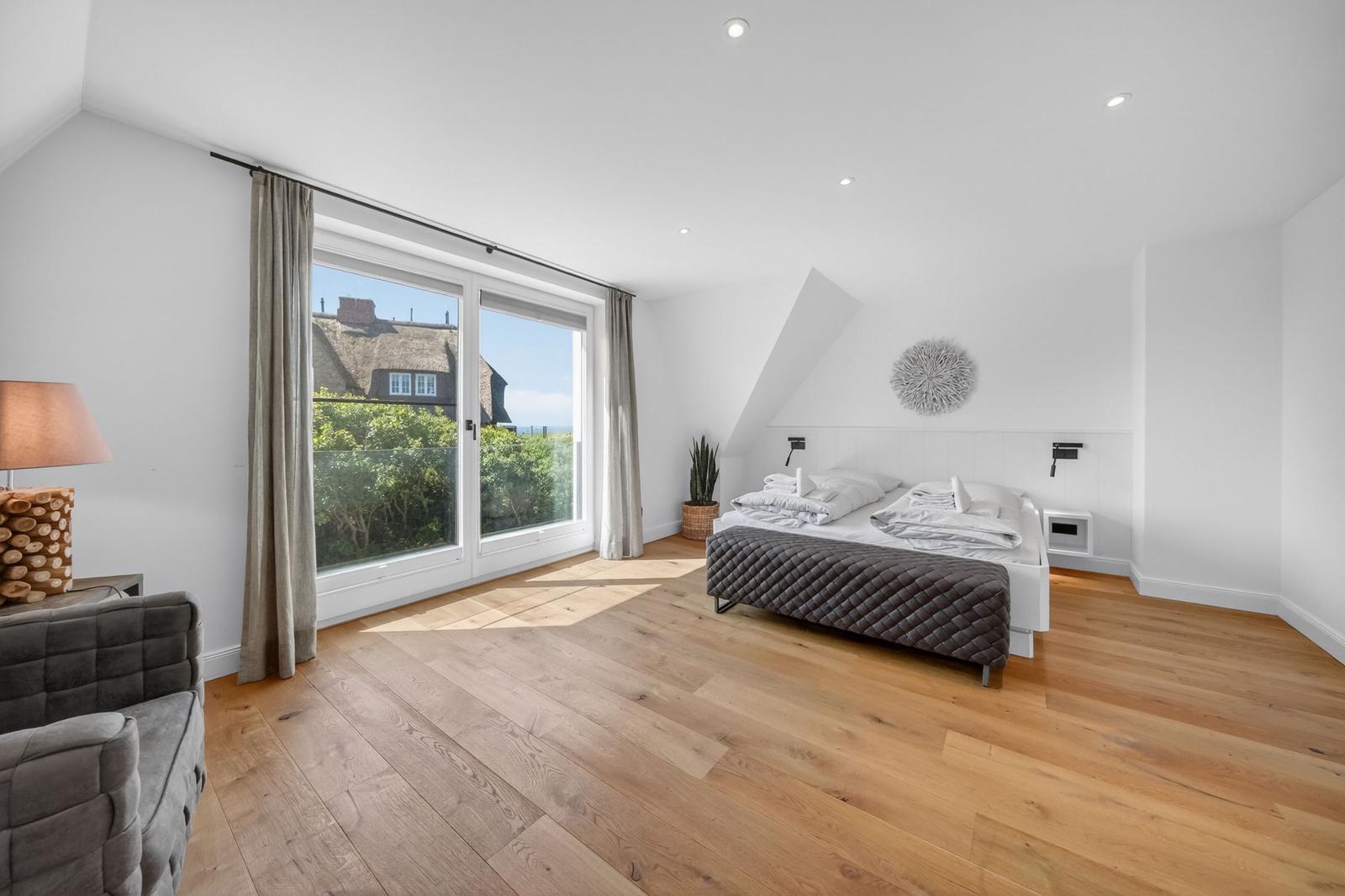 Schlafzimmer mit Dachschrägen, Holzboden und großem Fenster mit Blick.