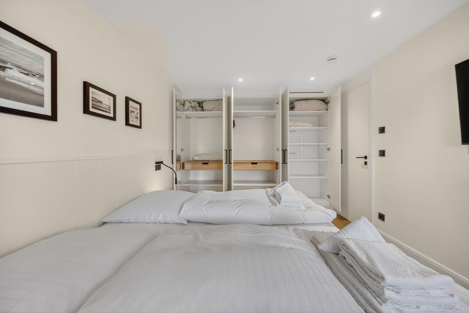 Schlafzimmer mit Bett, Kleiderschrank und Bildern an der Wand.