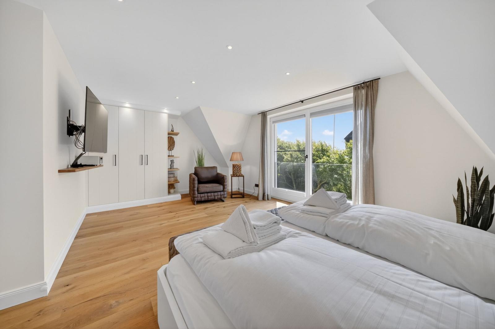 Schlafzimmer mit Doppelbett, TV und Balkonblick