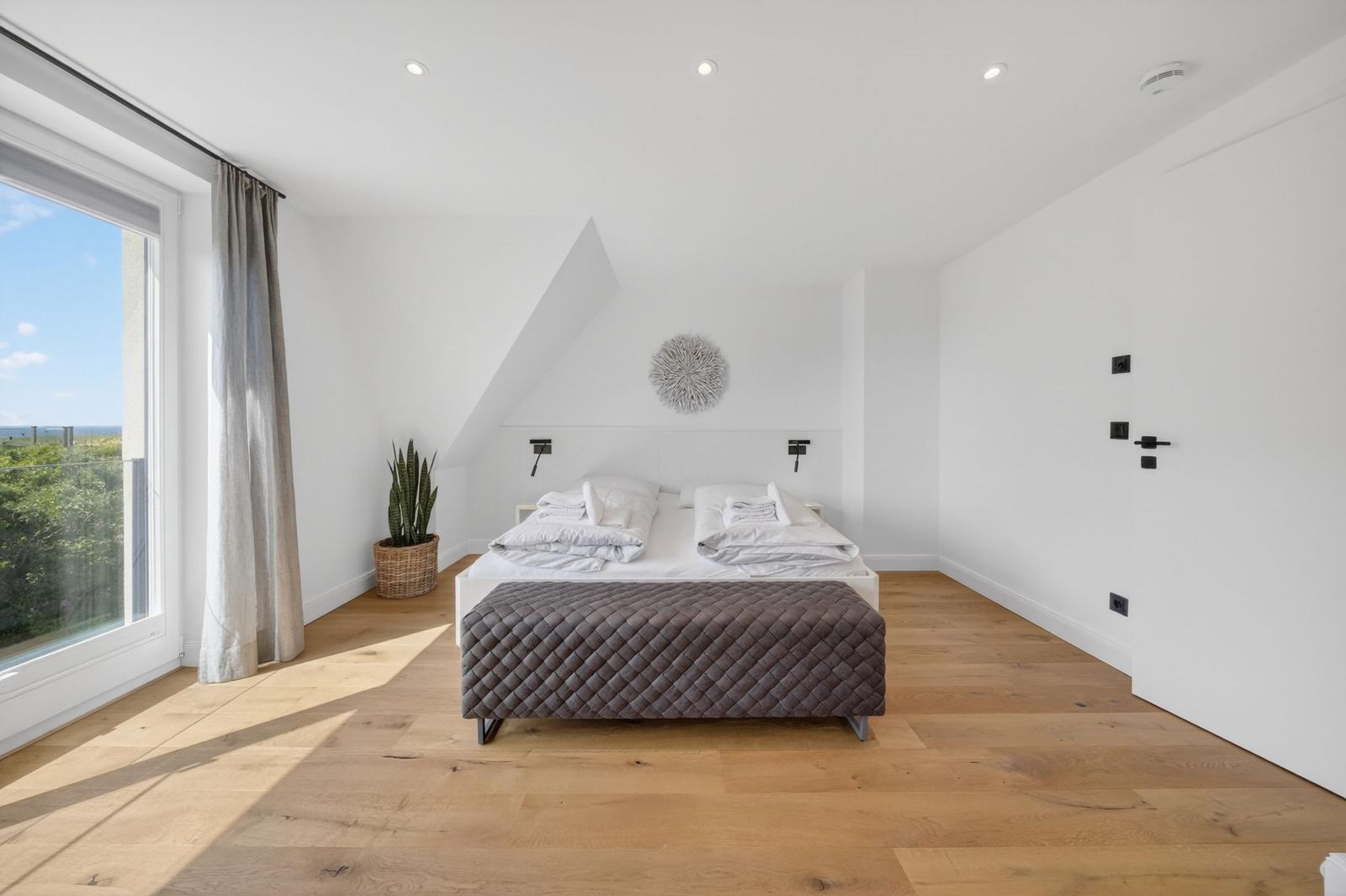 Schlafzimmer mit Dachboden, großem Bett und Blick auf die Landschaft.