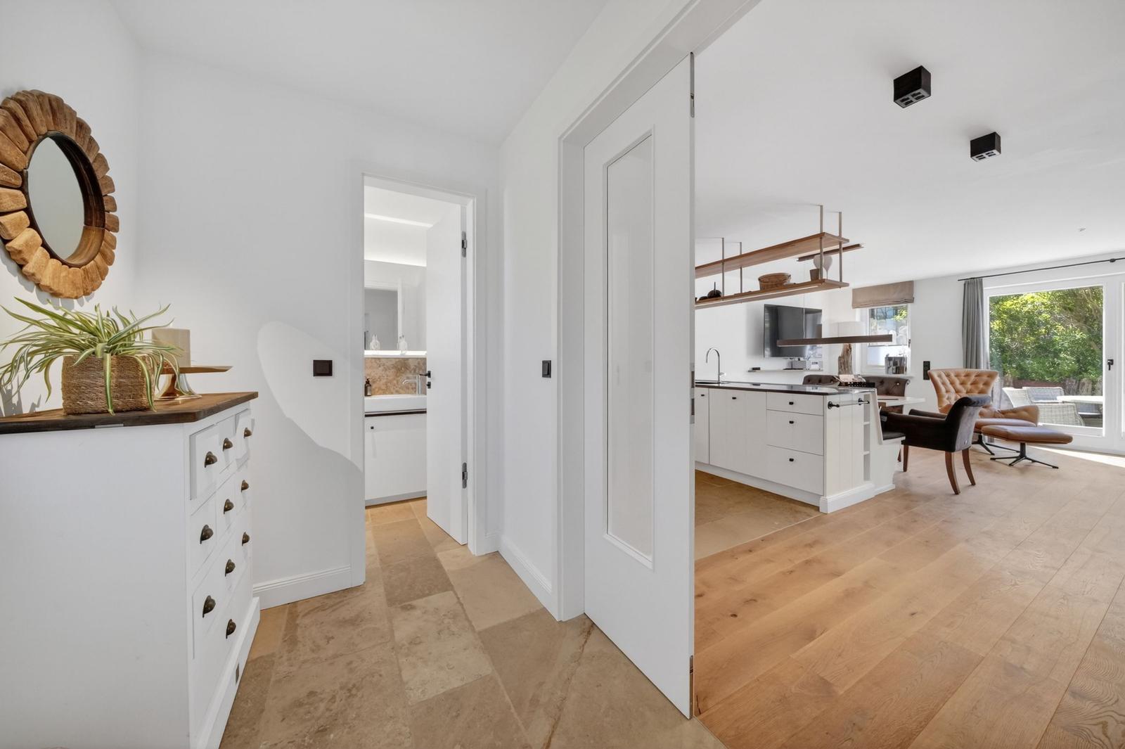 Haus mit Küche, Wohnbereich und Bad. Holzboden und weiße Wände.