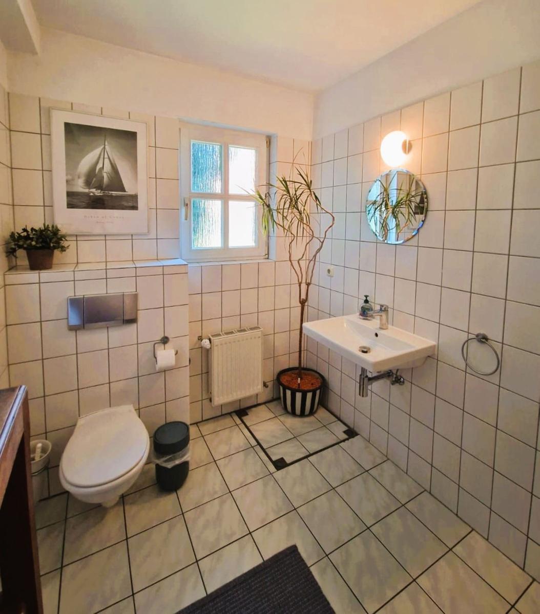 Badezimmer mit Toilette, Waschbecken und Pflanze an der Wand.