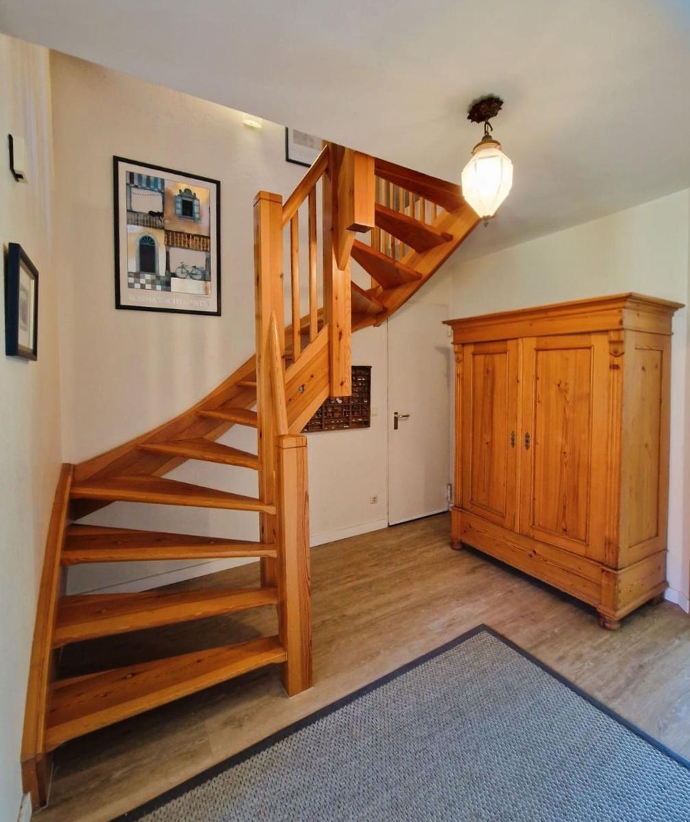 Holztreppe führt zur oberen Etage. Holzschrank und Teppichboden sichtbar.