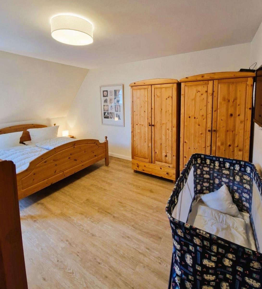 Schlafzimmer mit Holzbett, Kleiderschränken und Wiege.