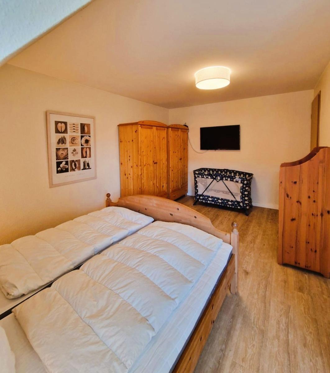 Schlafzimmer mit Doppelbett, Holzmöbeln und TV an der Wand.