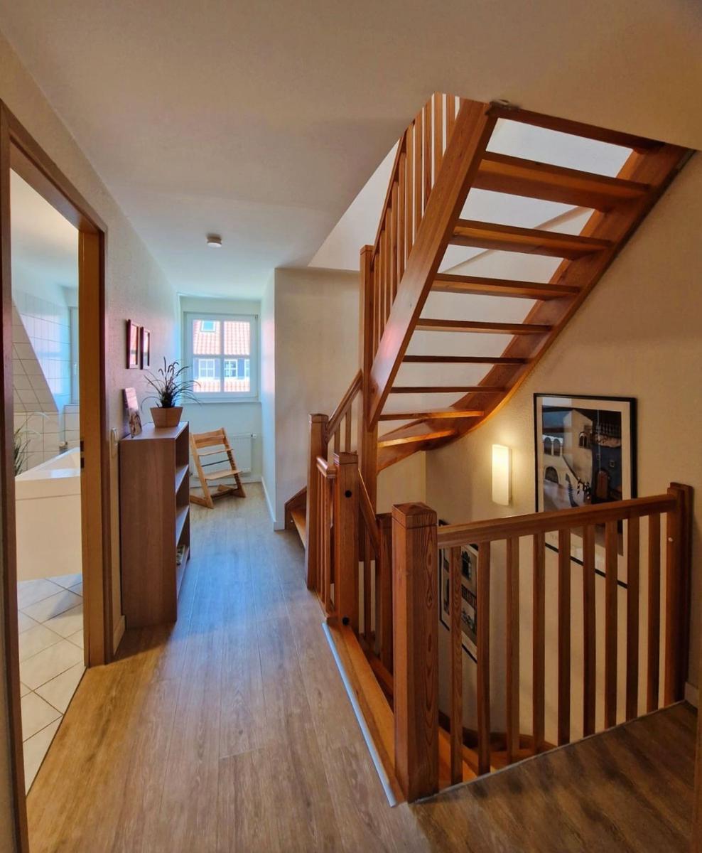 Haus mit Holztreppe, Flur und Blick in Bad und Wohnbereich.