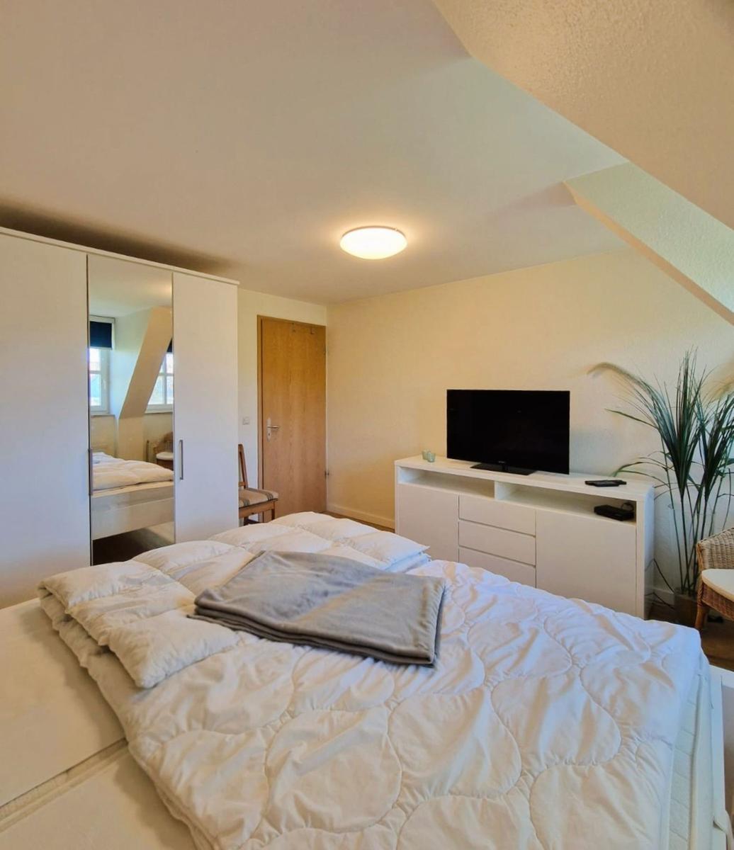 Schlafzimmer mit Bett, Kleiderschrank und Fernseher an der Wand.