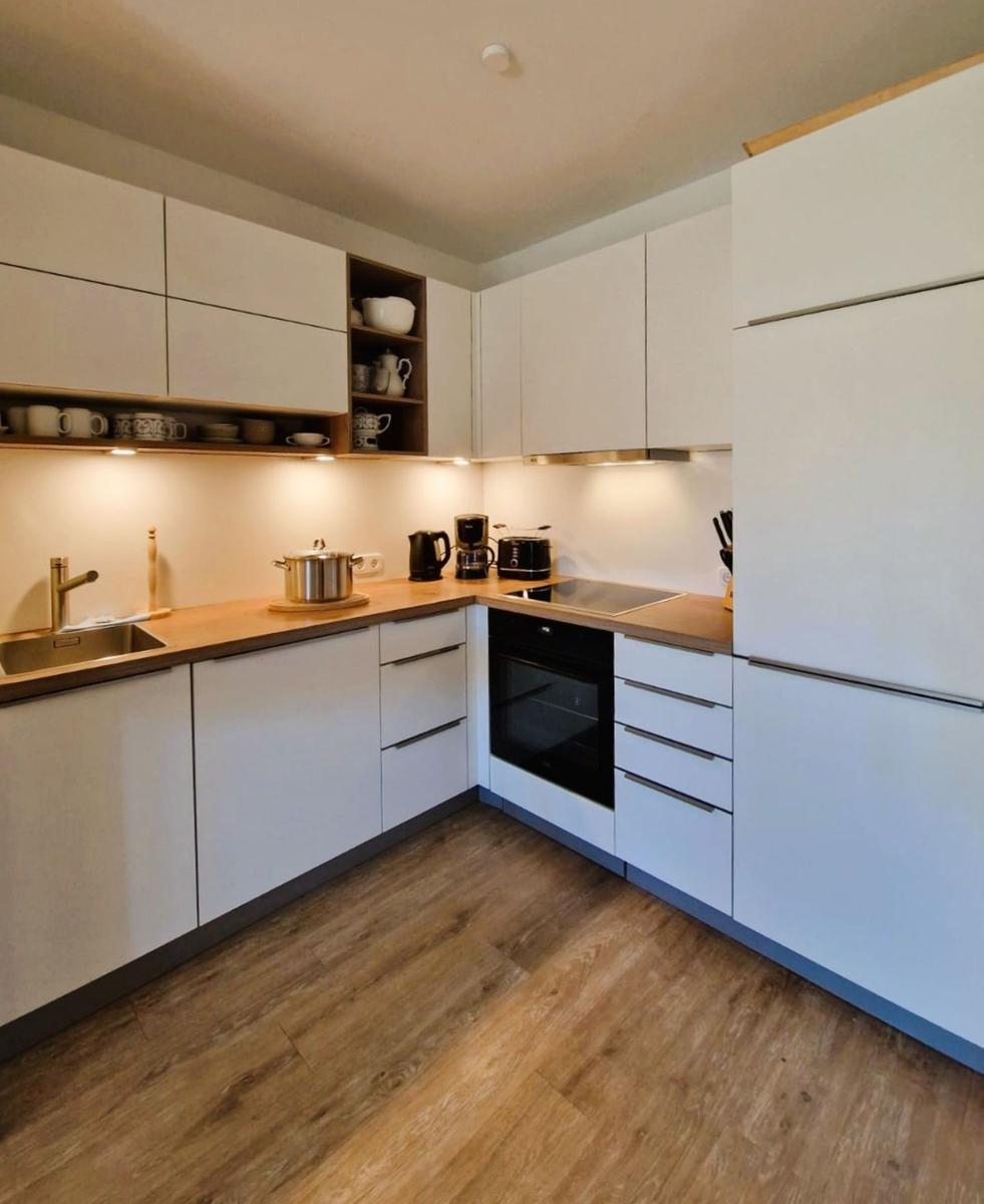Moderne Küche mit weißen Schränken, Holzwerkzeug und integriertem Ofen.