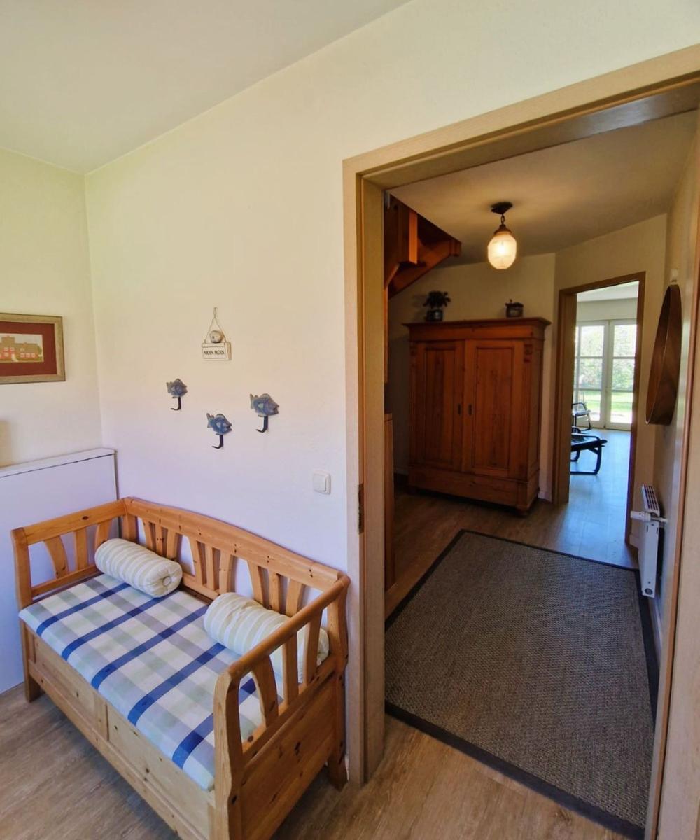 Ein Schlafzimmer mit Holzbett und Sicht auf Wohnbereich mit Kleiderschrank.