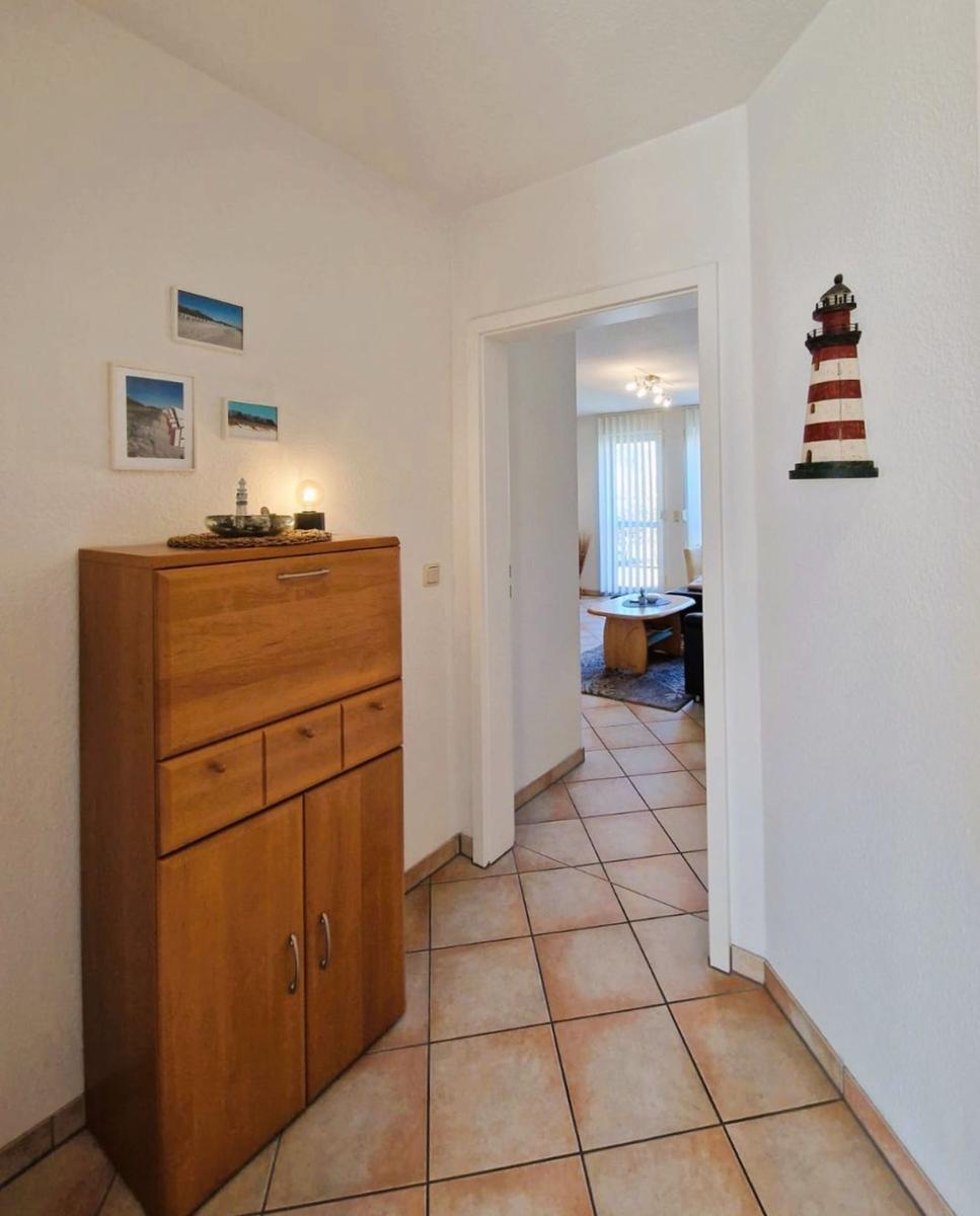 Hallenflur mit Holzschrank, Wandbildern und Laterne. Durchgang in Wohnzimmer.