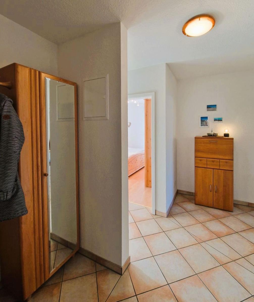 Flur mit Kleiderschrank und Blick in Schlafzimmer mit Holzboden.