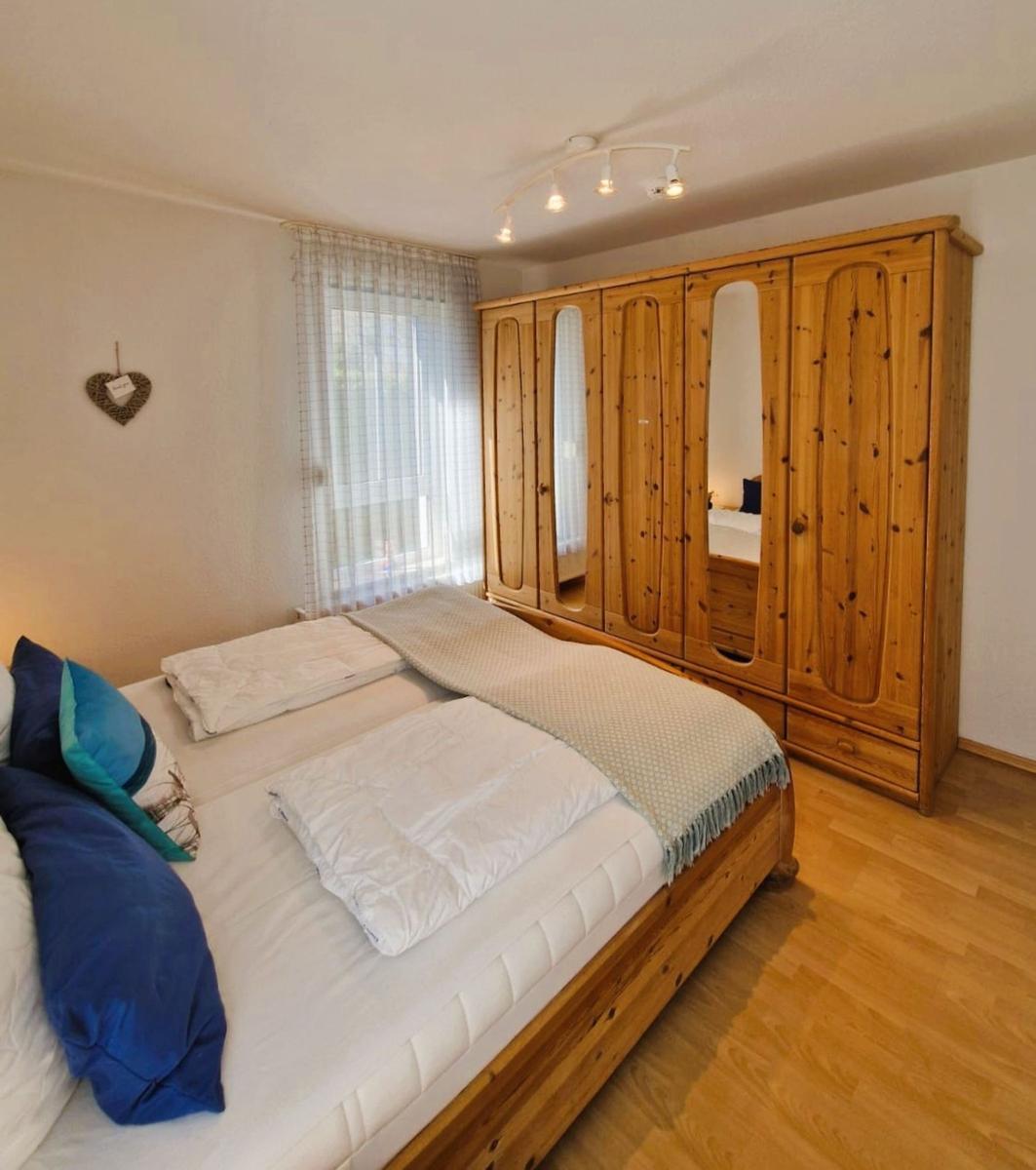 Schlafzimmer mit Holzbett und großer Garderobe mit Spiegeln.