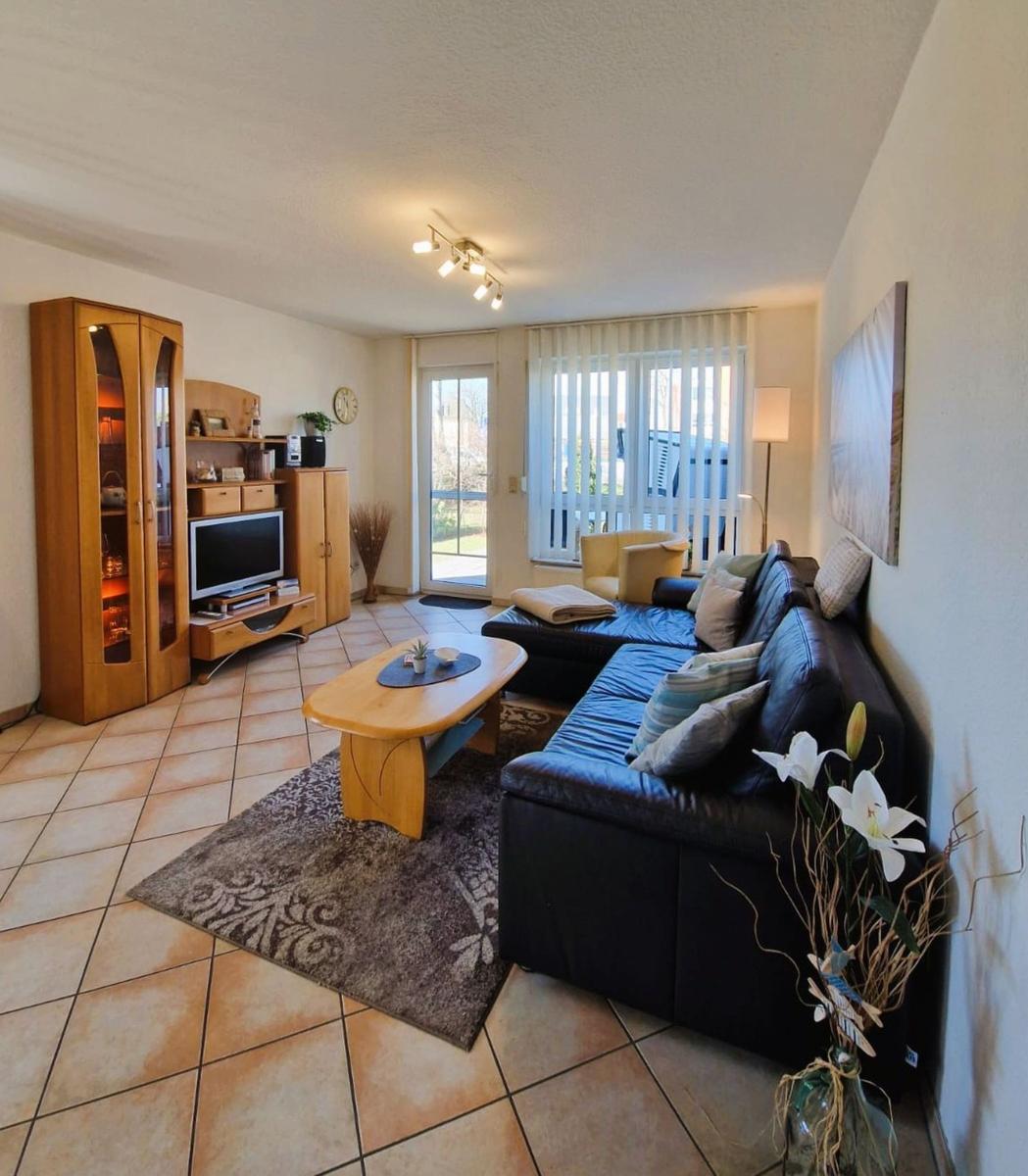 Wohnzimmer mit Sofa, Couchtisch und TV-Möbel. Terrasse über Glastür.