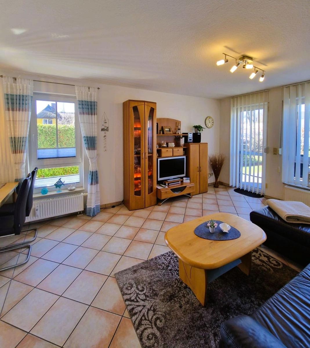 Wohnzimmer mit Holzmöbeln, Fernseher und Terrassentür.
