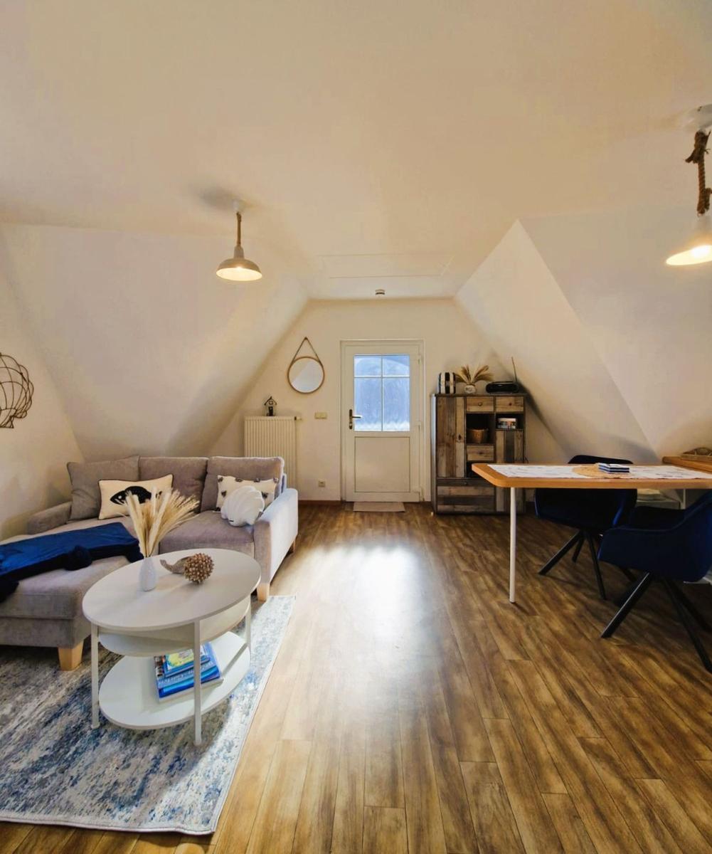 Wohn- und Essbereich mit Sofa, Tisch und Holzboden unter schrägen Dachdecken.