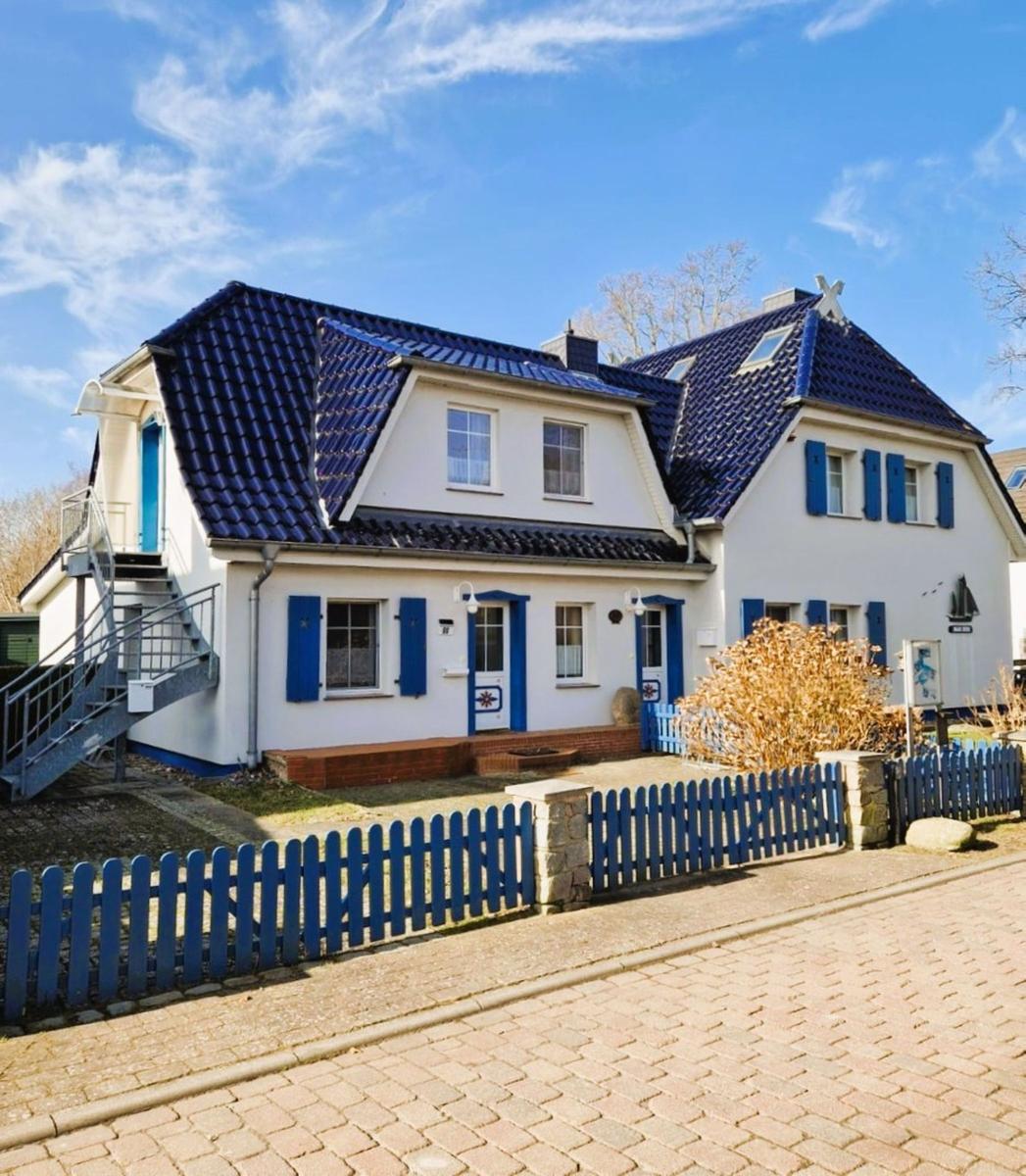 Wohnhaus mit blauem Dach und weißen Wänden, umgeben von einem blauen Zaun.