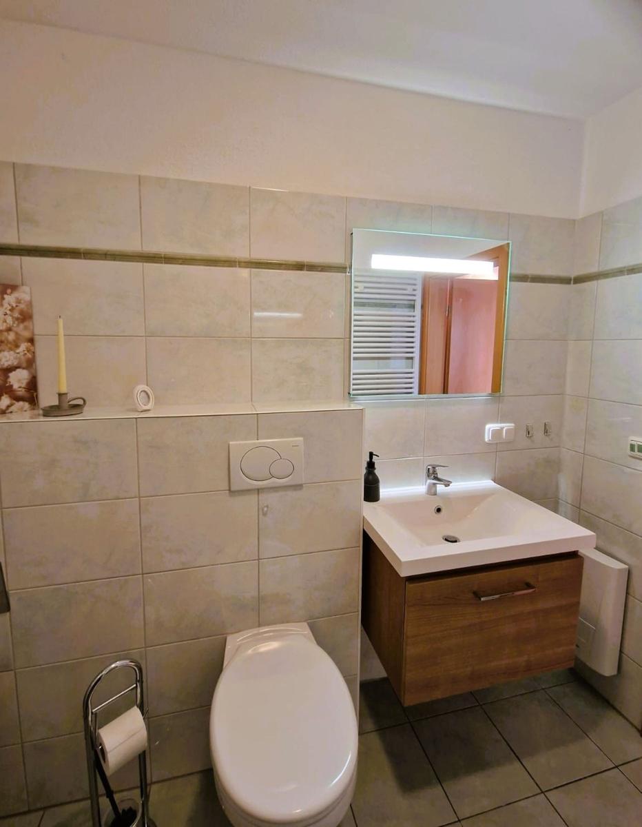 Badezimmer mit Toilette, Waschbecken und Spiegel