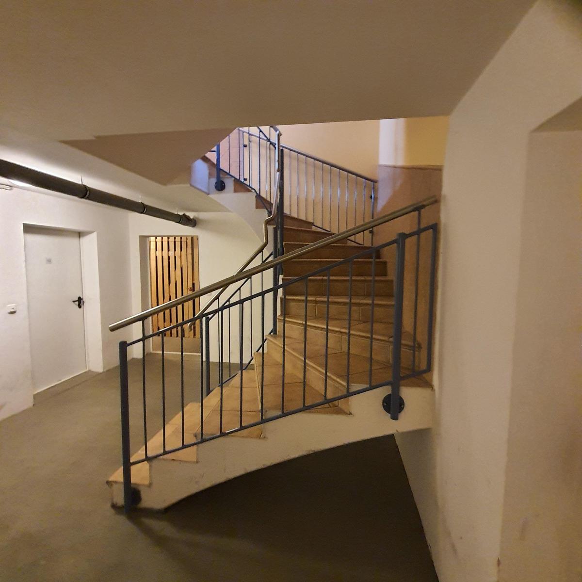 Treppe mit Metallgeländer führt nach oben. Nebenraum mit Tür und Holztor.