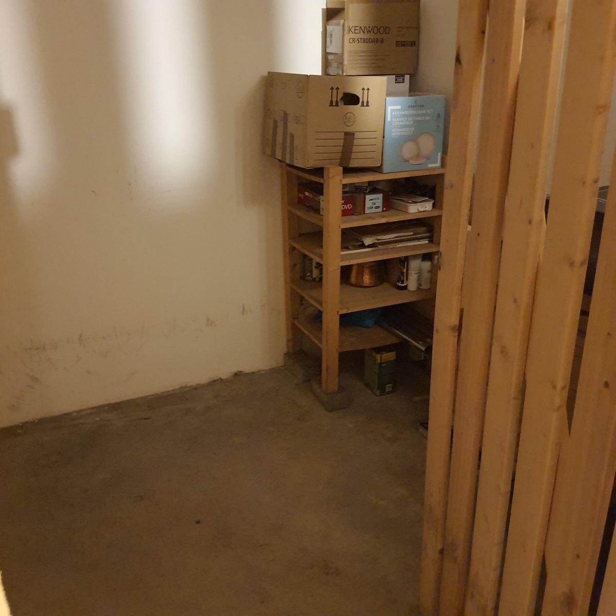 Ein Raum mit einem Holzregal, auf dem Kartons und Gegenstände stehen.