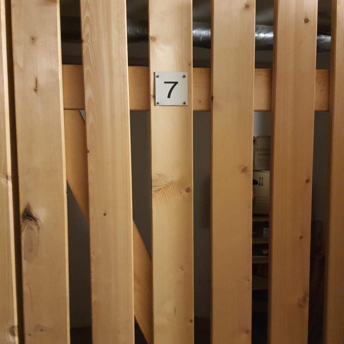 Holzgeländer mit Schild 7. Blick in einen Raum mit Regal und Boxen.
