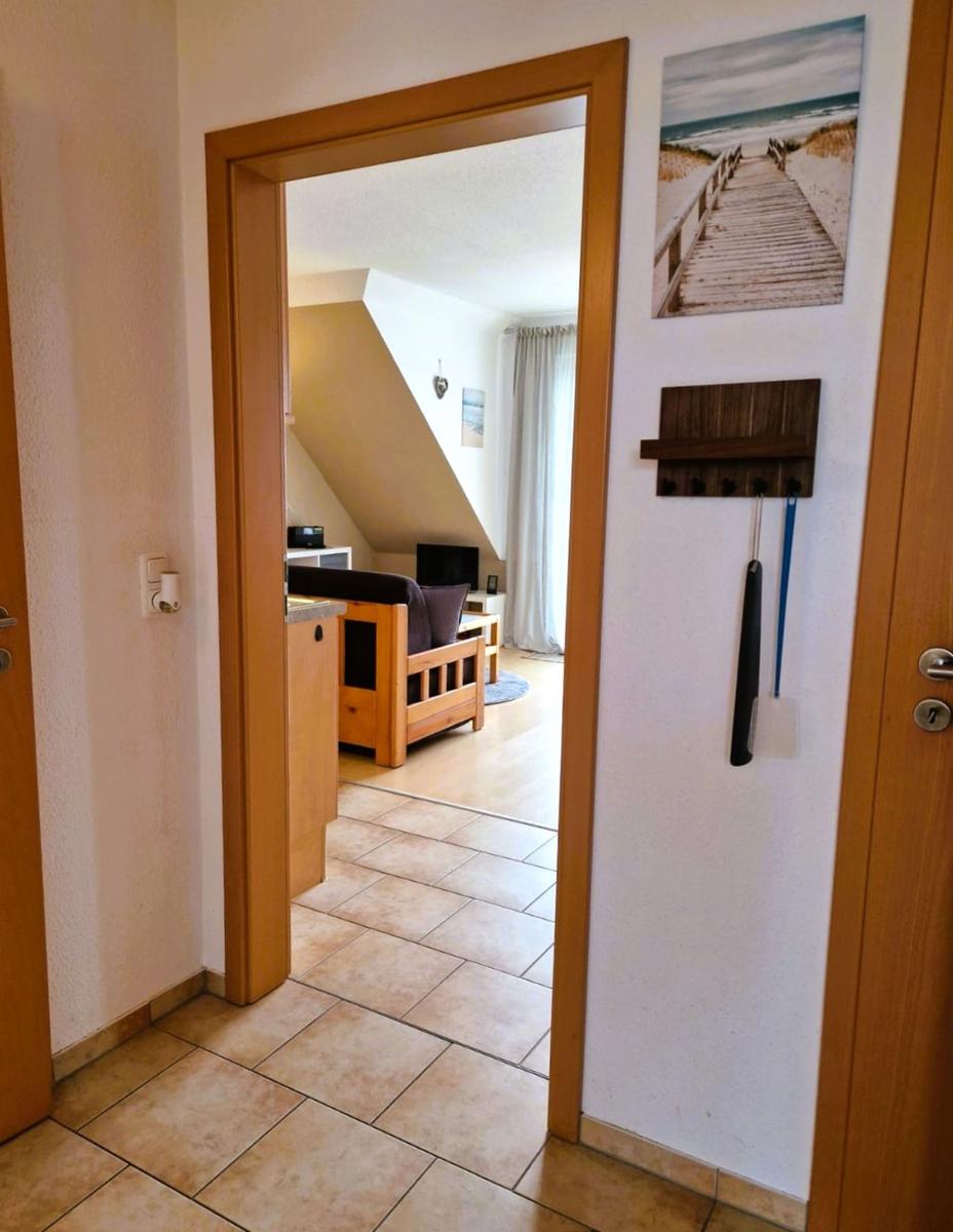 Durchgang zur Wohnung mit Holzrahmen, Wandbild und Haken für Schlüssel und Besen.