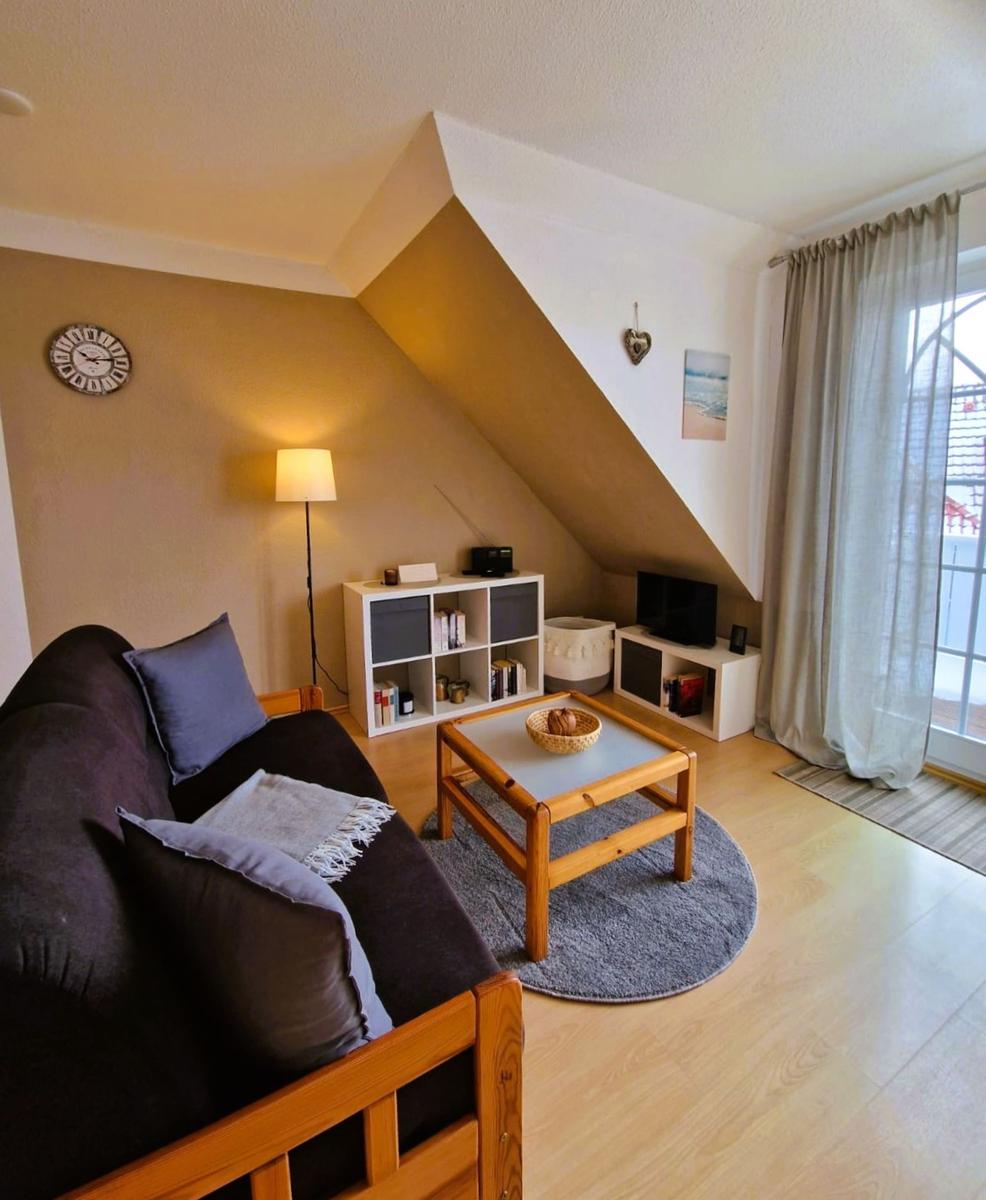 Wohnzimmer mit Sofa, Couchtisch und Bücherregal unter Dachschräge