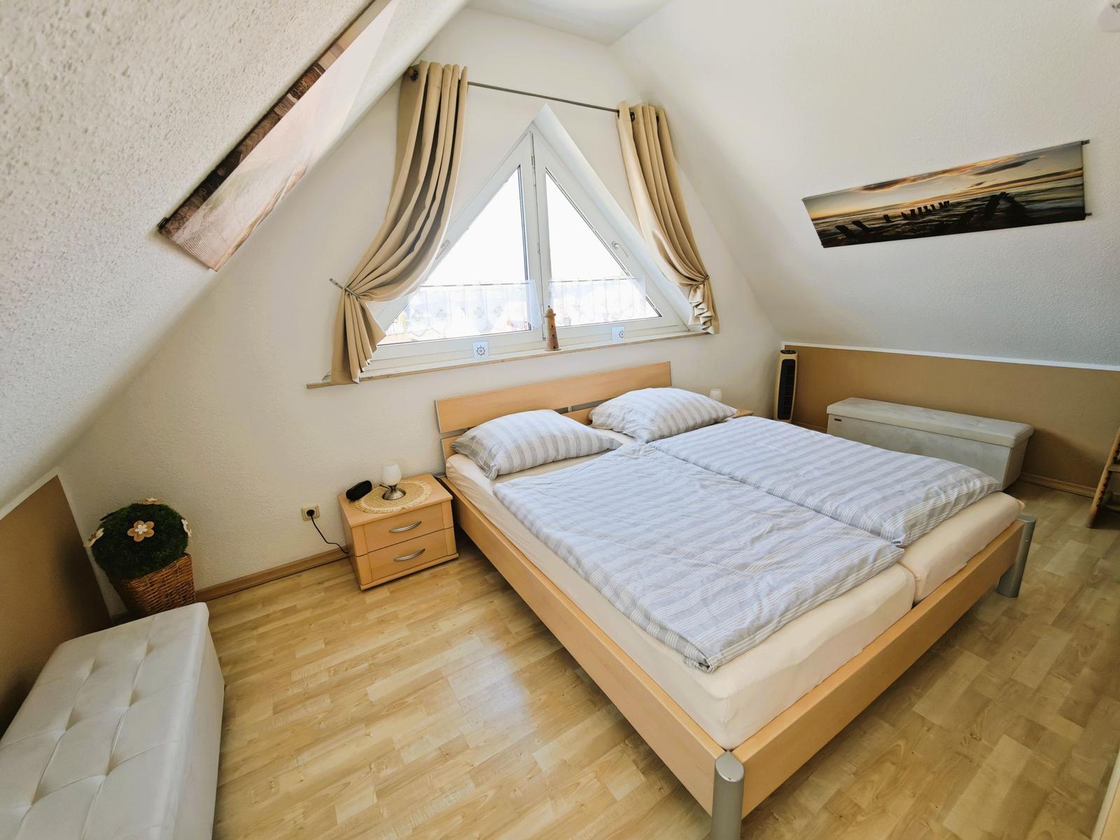 Doppelbettzimmer mit Dachschrägen, Fenster und Holzboden.