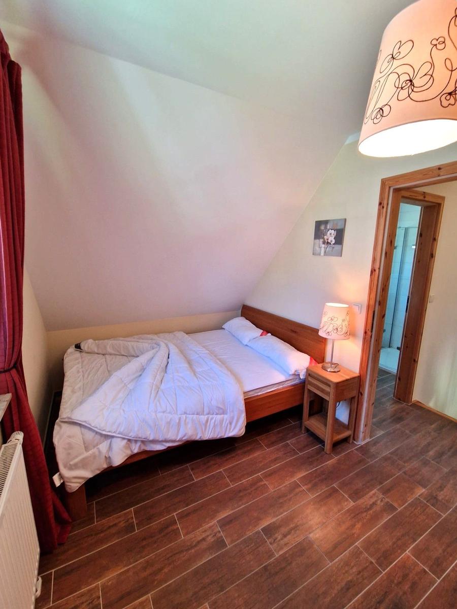 Schlafzimmer mit Dachschrägen, Holzboden und Bett mit weißer Bettwäsche.