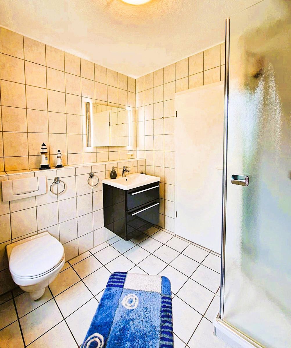 Bathroom with shower, sink and toilet. Tiled walls and floor.