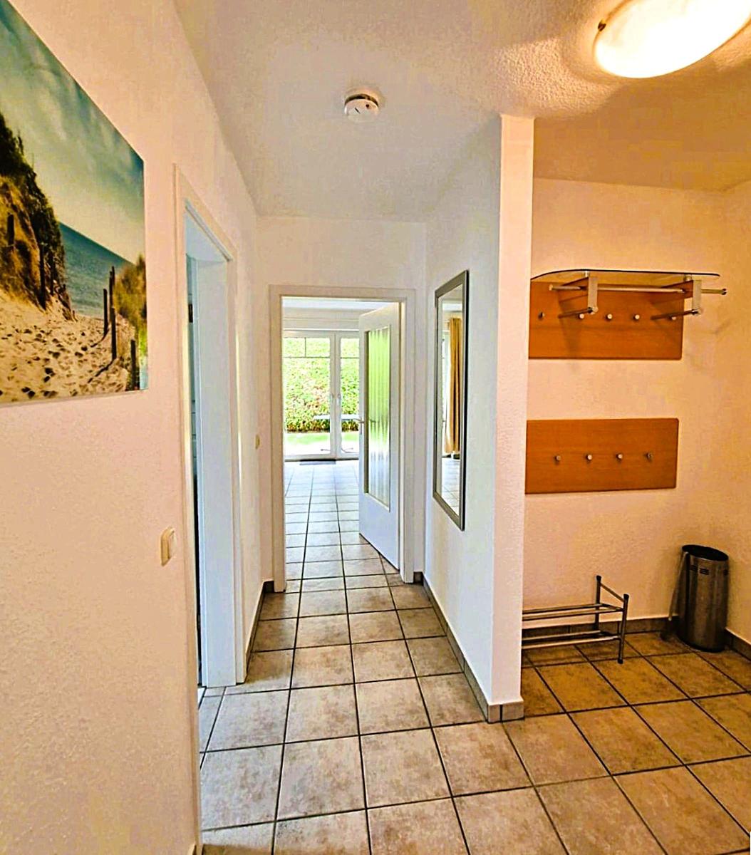 Hallway with tiled floor, wall picture, mirror, and coat area with hooks.