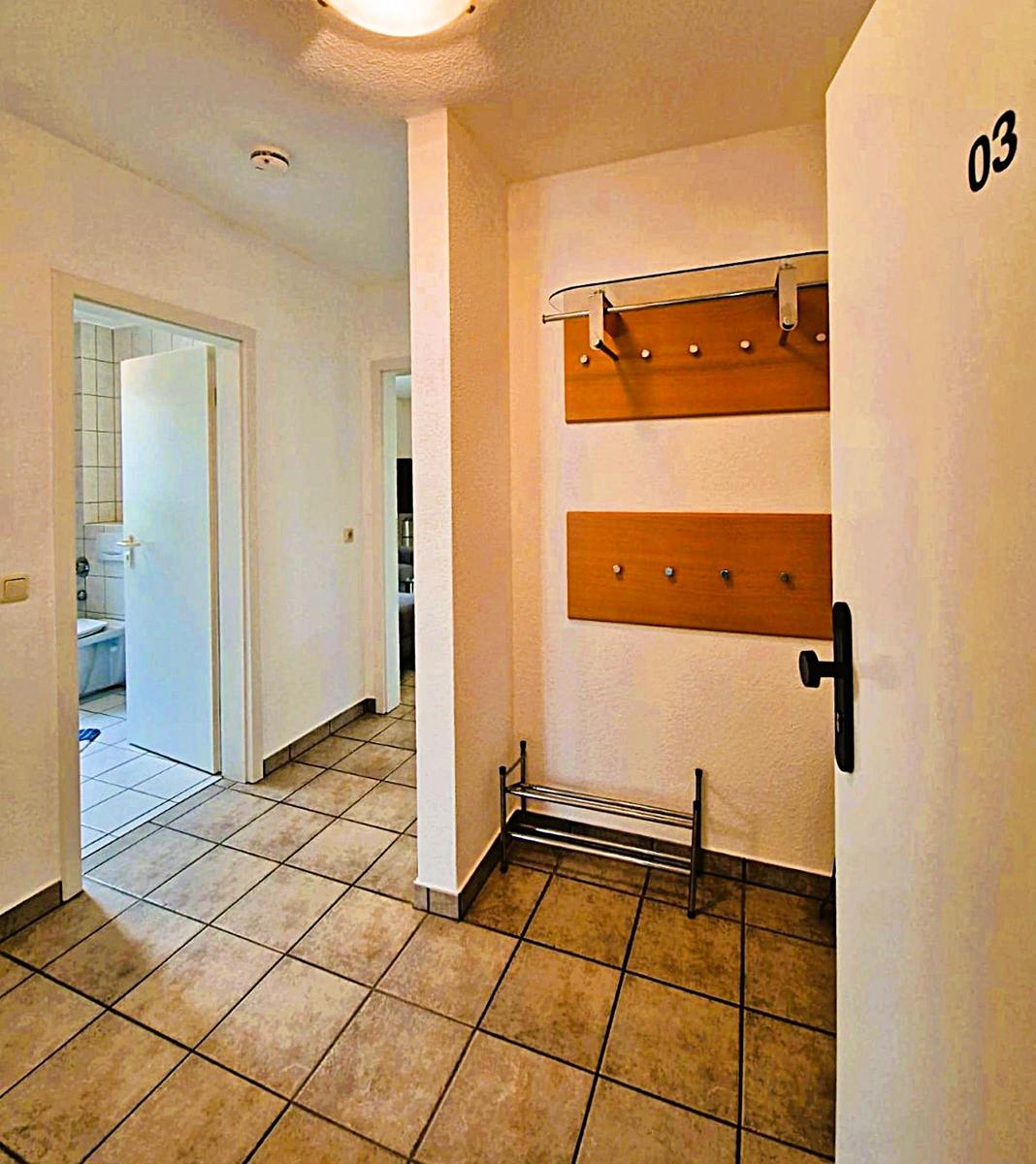 Entrance area with coat rack, shoe rack, and view into bathroom and kitchen.