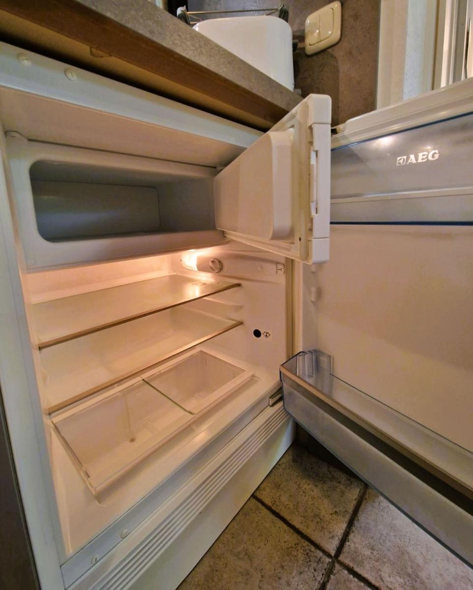 Empty refrigerator with open door and visible shelves.