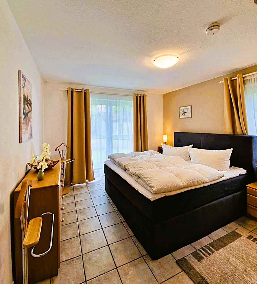 Bedroom with large bed, window with curtains and wooden furniture.