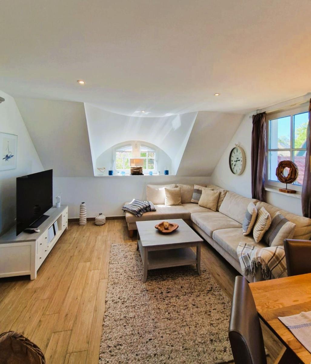 Wohnzimmer mit Sofa, Couchtisch und Fernseher unter Dachschrägen.