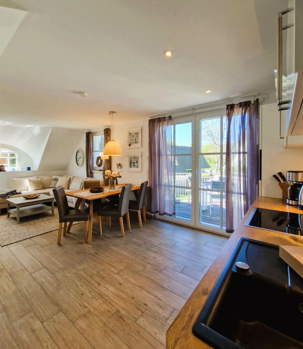 Küche, Essbereich und Wohnzimmer mit Holzboden und Glasfront zur Terrasse.