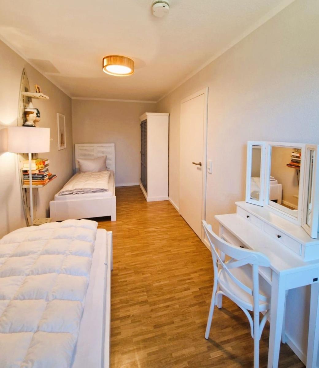 Zimmer mit zwei Betten, Schreibtisch und Holzboden.
