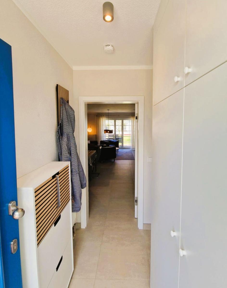 Flur mit Garderobe, weißen Schränken und Blick in das Wohnzimmer.
