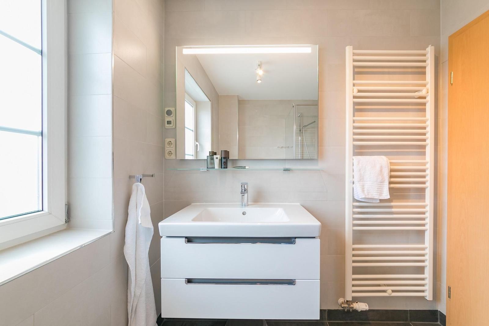 Badezimmer mit Waschbecken, Spiegel und Heizkörper