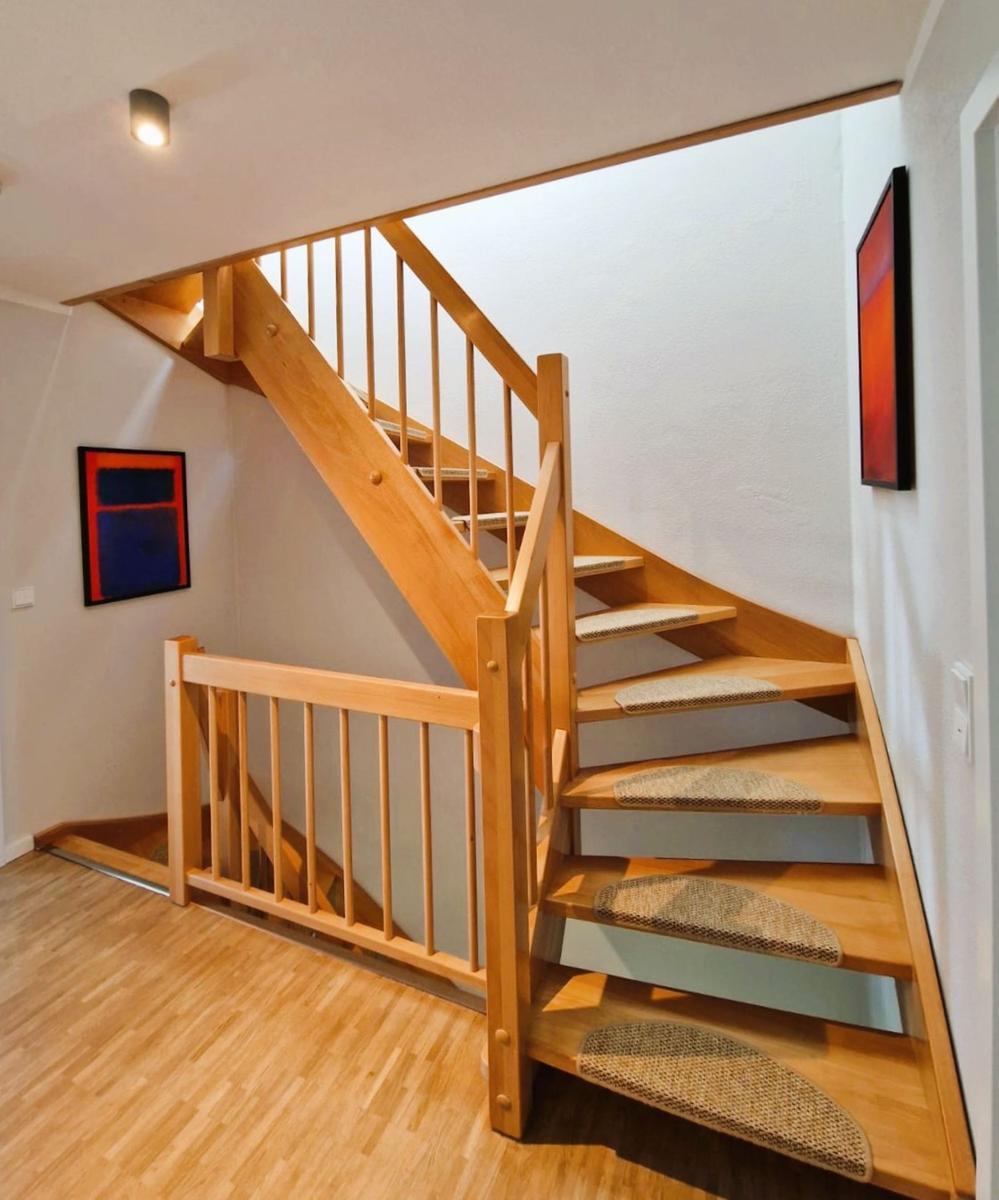Holztreppenhaus mit Sitzkissen und Wandbildern