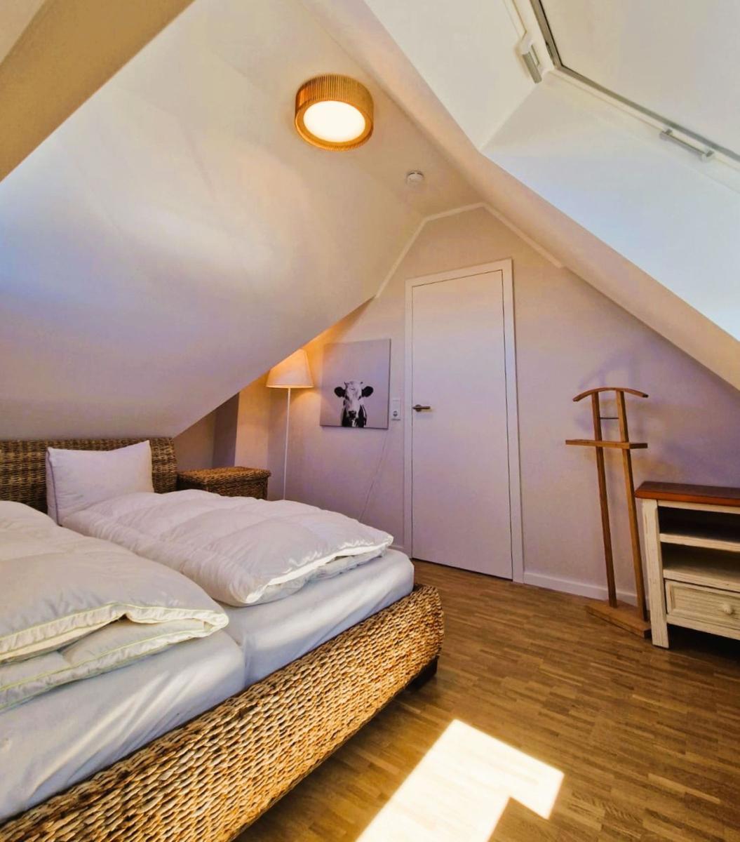 Schlafzimmer mit Dachschrägen, Bett, Kleiderständer und Holzboden.