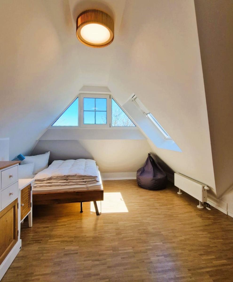 Dachgeschosszimmer mit Doppelschlafzimmer, Holzboden und Dachfenster.