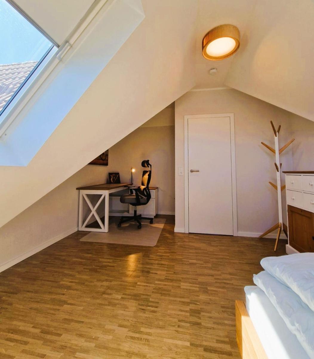 Schlafzimmer mit Dachfenster, Schreibtisch und Bett
