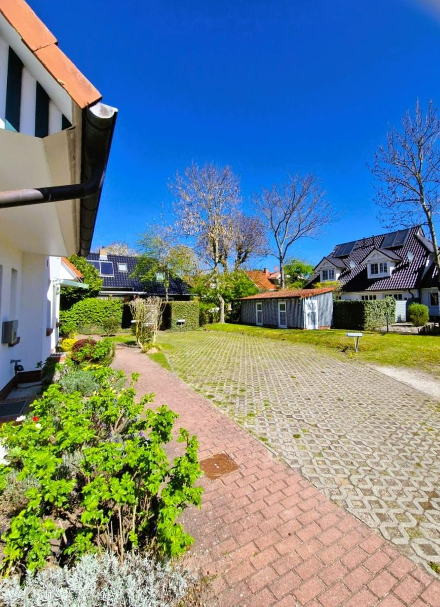 Haus mit Garten, gepflastertem Weg und blauem Himmel.
