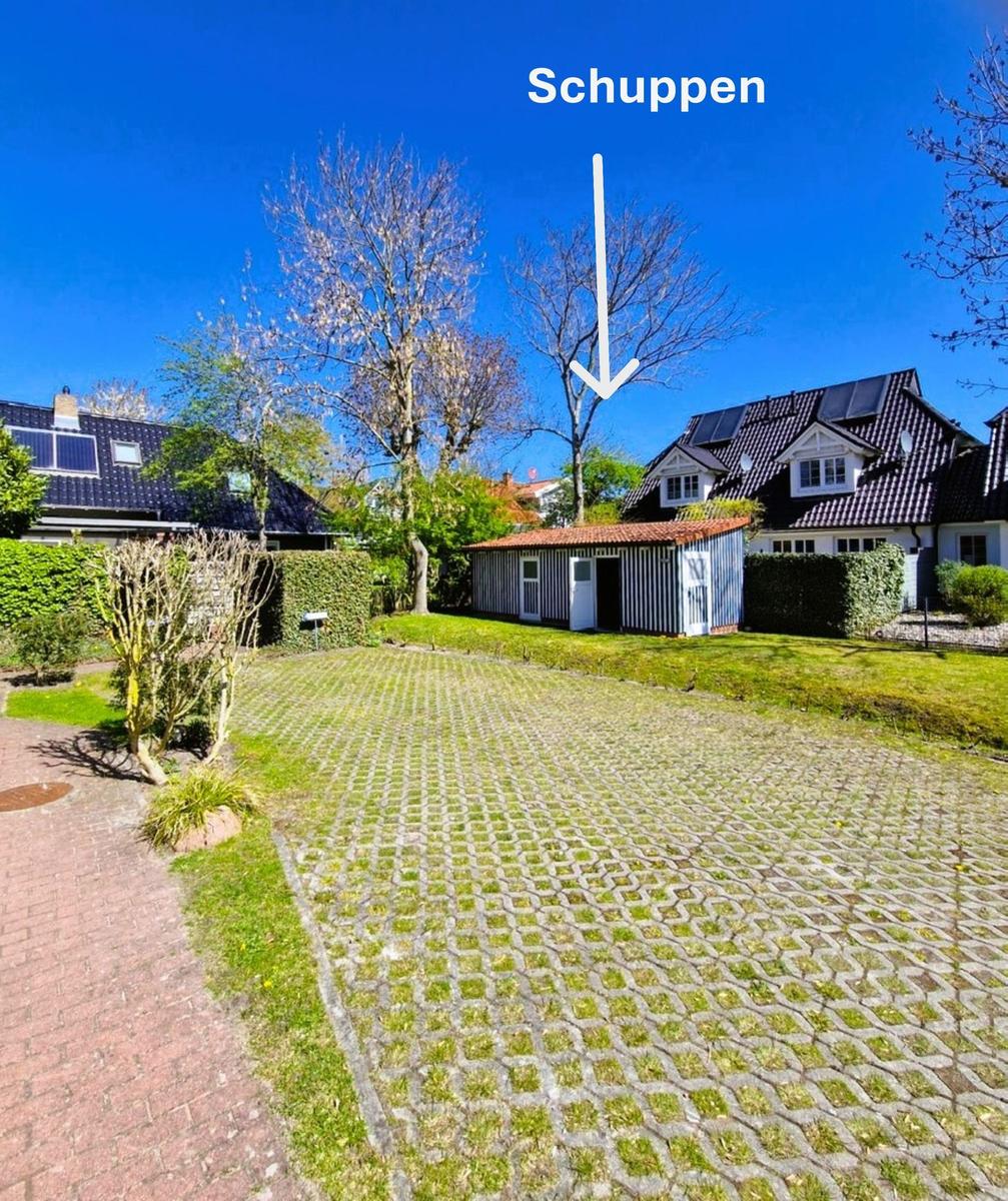 Schuppen mit rotem Dach im Garten zwischen zwei Häusern.