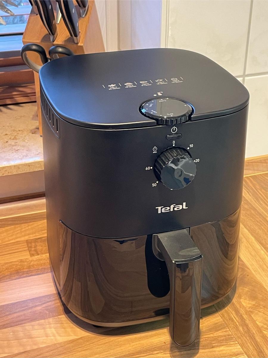 Schwarze Tefal Luftfritteuse mit Drehregler und Bedienfeld auf Holzoberfläche.
