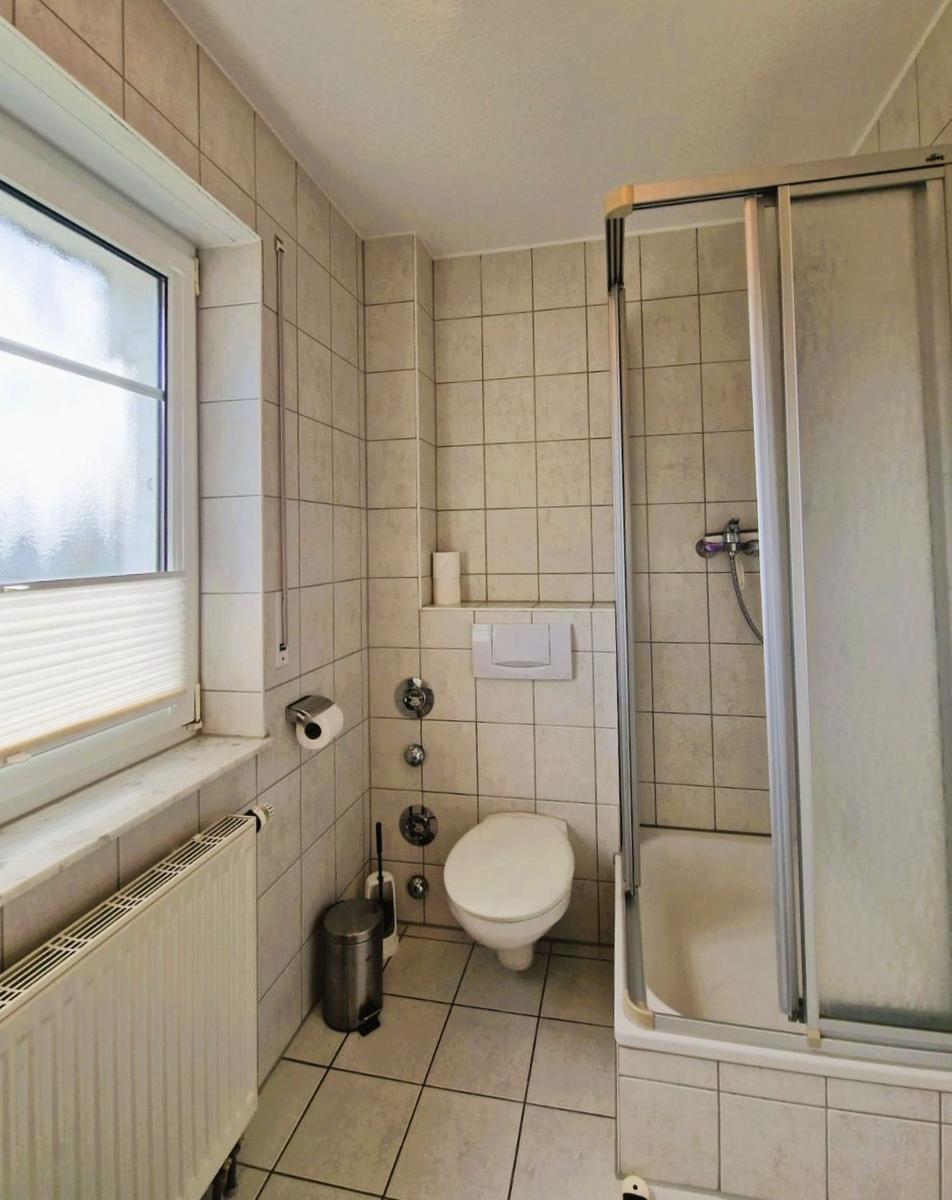 Badezimmer mit Dusche, Toilette und Fenster